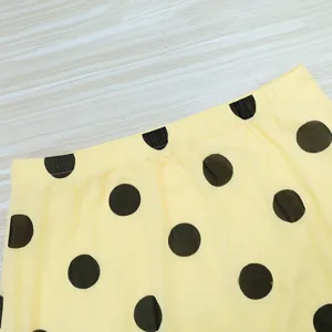 Detail of women's yellow black polka dot mesh double layer skirt fabric texture.