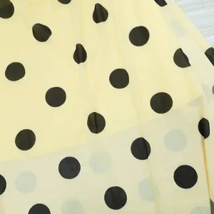 Close-up detail of yellow polka dot mesh fabric, showing soft double-layer draped texture.