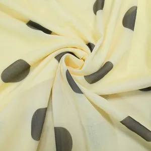 Detail shot of light yellow mesh fabric with dark polka dots, soft texture and draping effect.