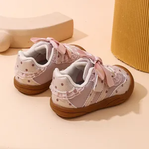 Dettaglio scarpe neonata primi passi, suola morbida con fiocco rosa e graziosi pois decorativi.