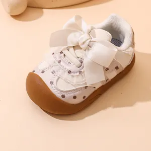 Primo piano di scarpe primi passi per neonati con fiocco carino e pois marroni.