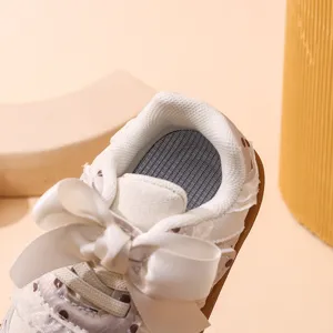 Primo piano dettagliato di scarpe da camminata per neonate con fiocco in raso e fodera in rete.