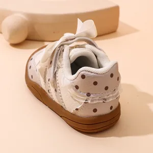 Primo piano dettaglio di scarpetta sneaker per bimba con pois e fiocco bianco morbido.