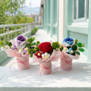 Handmade crochet flower bouquet in pink paper bucket, detailed outdoor tabletop display.