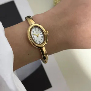 Nahaufnahme einer eleganten goldenen ovalen Armreif-Uhr mit weißem Zifferblatt.