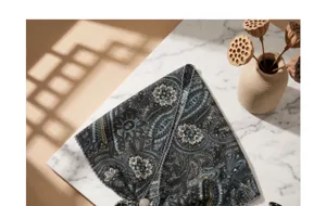 Detailed view of the vintage paisley triangular scarf with beaded edge on a marble surface.