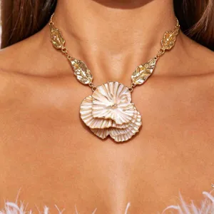 Detailed view of the gold statement necklace featuring layered floral pendant and leaf links.