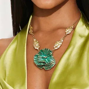 Detailed close-up of statement layered flower pendant necklace with metallic gold leaves and green enamel.