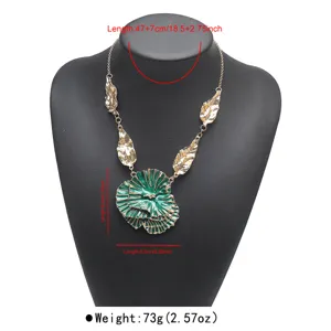Detailed close-up of the exaggerated green layered flower pendant necklace with gold leaves.