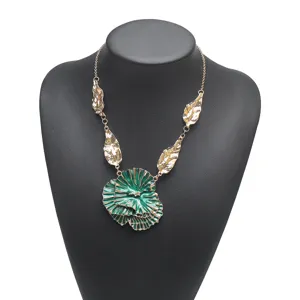Close-up detail of the exaggerated green pleated flower pendant necklace with gold leaves.