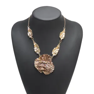 Detailed view of statement metallic gold ruffled flower pendant necklace with leaf charms.