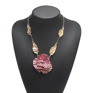 Exquisite 3d flower pendant and gold leaf detail on metallic chain necklace close-up view.