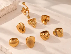 Primer plano de anillos llamativos asimétricos abstractos de acero inoxidable dorado.