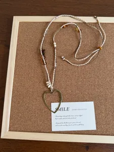 Primo piano dettagliato della collana maglione di perle in pietra naturale con cuore in metallo.