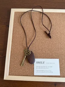 Collana con ciondolo a chiave e cuore vintage con cordino marrone e pietra, vista dettagliata.