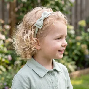 Girls green fabric headband with bow, toddler safe hair accessory for cute daily wear styling.