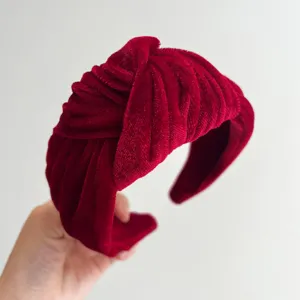 Close-up detail of a red velvet knotted headband, showing soft fabric texture and wide design.