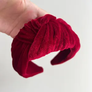 Red velvet knotted headband detail shot showcasing soft fabric and elegant twisted design.