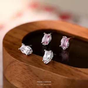Nahaufnahme von unregelmäßigen rosa und weißen Kristall Ohrringen auf Holzablage.