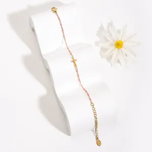 Minimalist stainless steel cross bracelet detailed with pink enamel beads and adjustable chain.
