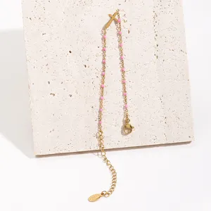 Minimalist stainless steel cross bracelet with pink enamel beads, elegant gold chain style.