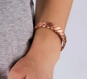 Bracciale rigido magnetico in rame con dettaglio intrecciato, mostrando lo stile vintage.