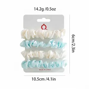 Satijnen haarscrunchies set in wit en blauw, gepresenteerd op kaart met gewichtspecificaties.