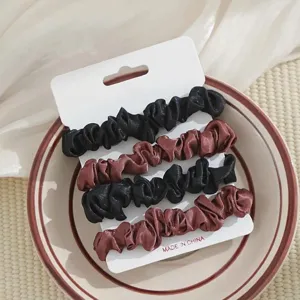 Detailopname van satijnen haarrekkers set in zwart en bruin kleuren op keramische schaal.