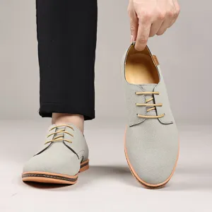 Detail view of men casual suede lace-up shoes in light grey with yellow shoelaces and flat sole.