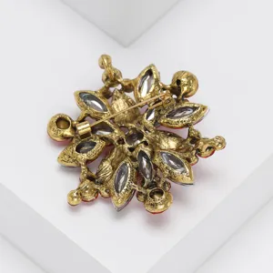 Close-up detail of vintage gold-tone crystal rhinestone brooch back pin structure display.