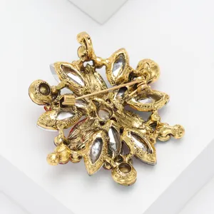 Vintage crystal rhinestone floral brooch pin, elegant gold tone metal costume jewelry accessory for women.