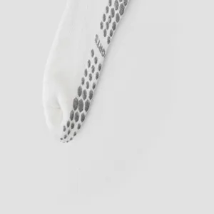 Detailopname van de witte anti-slip yogasokken zool met grijze gripstippen voor fitnesstraining.
