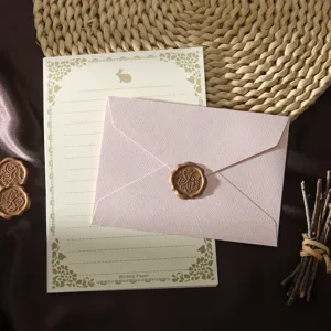 Set de papeterie vintage avec enveloppe texturée rose, papier ligné et cachet de cire.