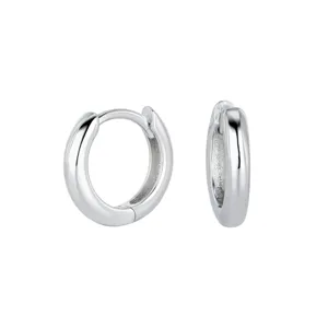 Gros plan détaillé de boucles d'oreilles créoles argentées avec surface polie et fermoir.