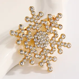 Close-up detail view of a sparkling gold snowflake brooch encrusted with clear rhinestones.
