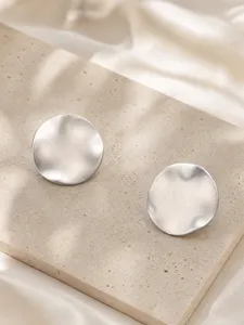 Gros plan détaillé mettant en valeur la texture des boucles d'oreilles rondes en métal.