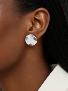 Vue de détail en gros plan d'une boucle d'oreille minimaliste en métal brossé irrégulier.