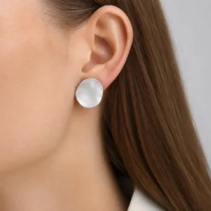 Gros plan de boucles d'oreilles puces en métal brossé irrégulier, texture métallique élégante.