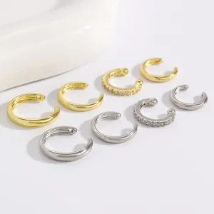 Vista detallada del juego de pendientes de oreja en C multicapa, oro y plata minimalistas.
