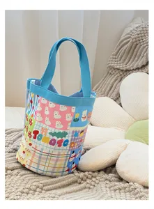 Détail du sac seau en toile mignon avec motifs de dessins animés et anses bleues.
