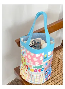 Vue détaillée du sac seau en toile avec un design patchwork coloré et des poignées bleues.