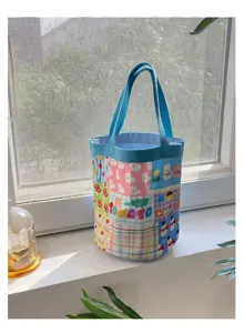 Détail de sac seau en toile mignon avec motifs de dessins animés et poignées bleues pratiques.