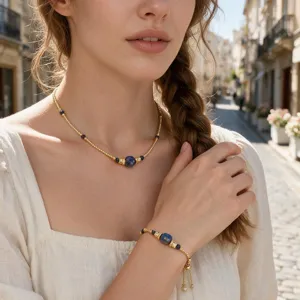 Detailed close-up of gold beaded necklace and matching bracelet with blue stones worn.