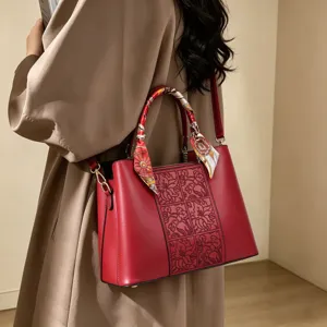 Borsa a tracolla in pelle rossa con pannello floreale goffrato e manico con foulard in seta.