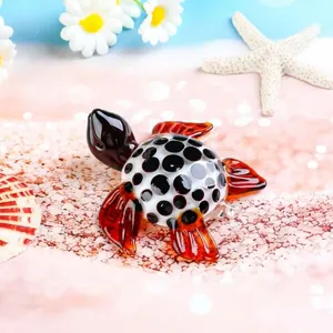 Detailed shot of glass sea turtle figurine with black spots and amber flippers on sand beach.