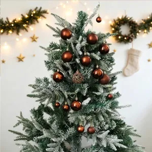 Dettaglio ravvicinato di un albero di Natale innevato decorato con eleganti palline marroni.