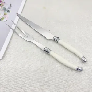 Ensemble couteau à steak et fourchette en acier inoxydable avec manche blanc.