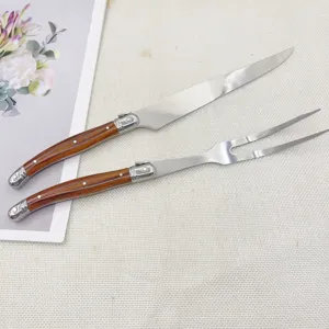 Ensemble couteau et fourchette à découper en acier inoxydable avec manche en bois.