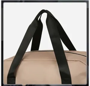 Detailed close-up of durable widened handle on travel duffel bag, showing sturdy black webbing.