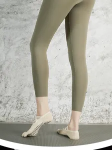 Detail shot of women's non-slip five-finger pilates yoga socks with cross straps, indoor.